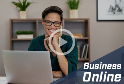 A smiling woman with glasses sits at a desk with a laptop, promoting 